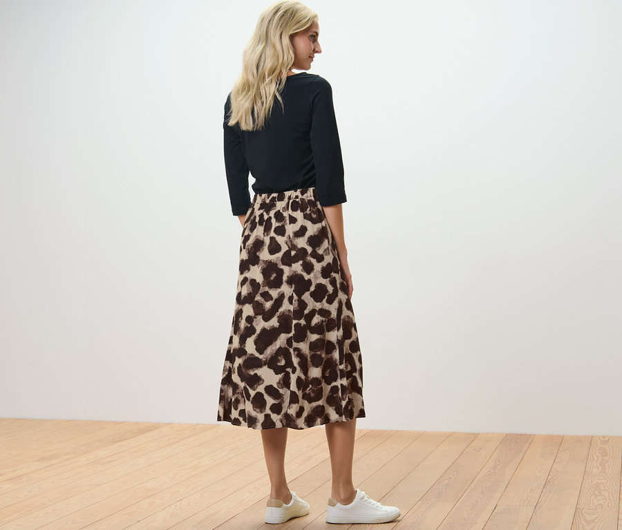 Une femme, vue de dos, porte une jupe midi imprimée.