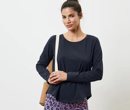 Une femme porte un t-shirt de sport manches longues bleu foncé et un legging à motifs.