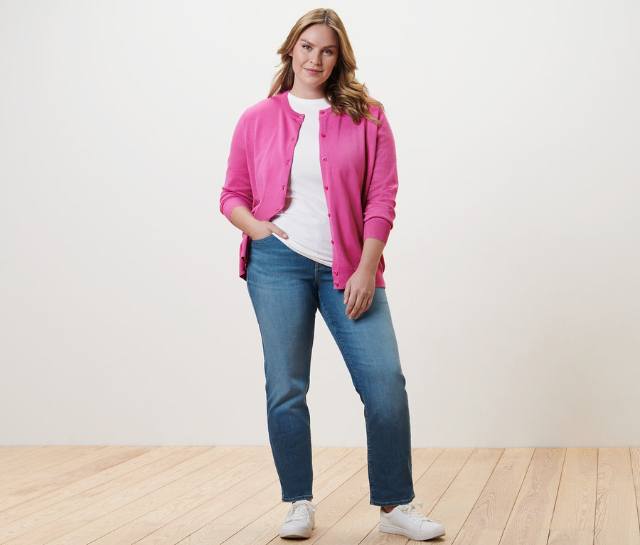 Femme posant en jean droit - Fit « Kira », t-shirt à manches 3/4 blanc et cardigan en maille fine.