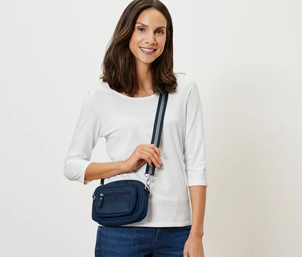 Femme posant avec un sac de sécurité à bandoulière bleu marine.