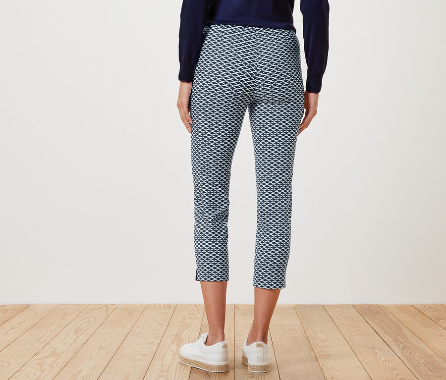 Vue arrière d'une femme portant un pantalon stretch imprimé 7/8 et des baskets blanches.