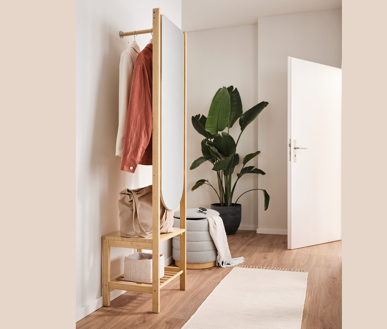 Pouf avec espace de rangement, sac, vêtements et portant à vêtements avec miroir dans un intérieur.