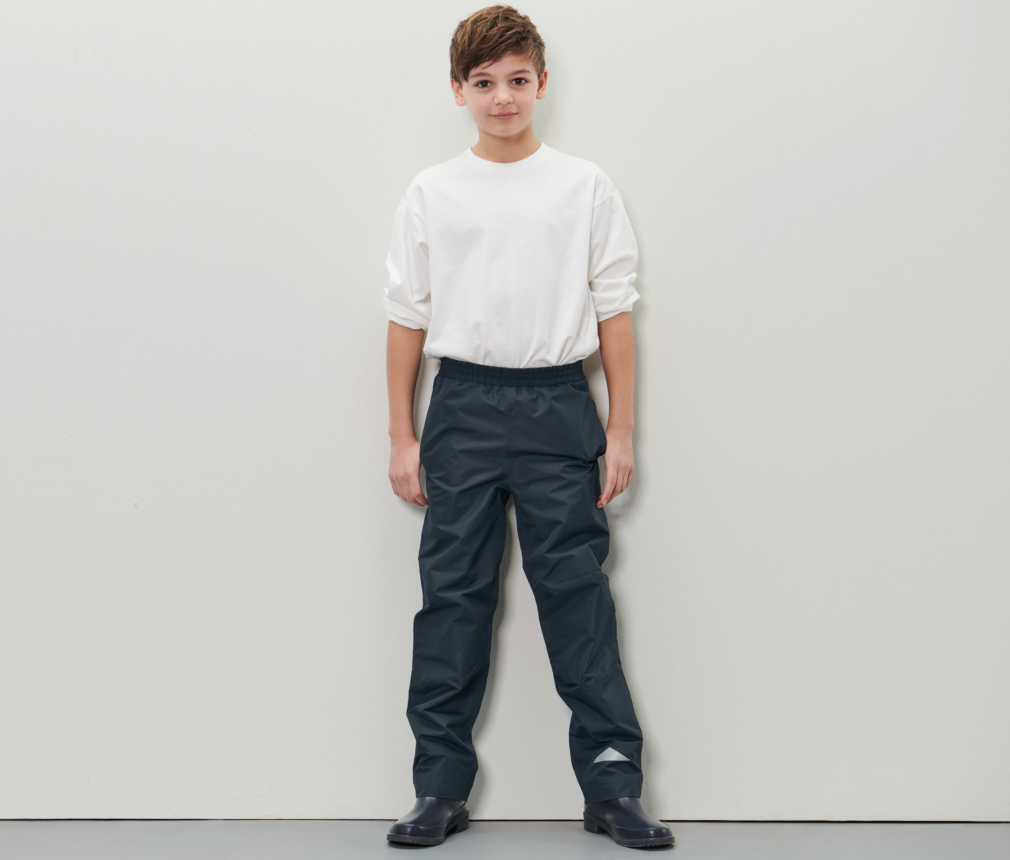 Garçon debout portant un pantalon imperméable pour enfant.