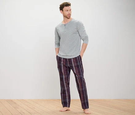 Un homme portant un haut de pyjama gris et un pantalon tissé.