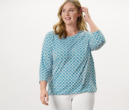 Femme posant, portant une blouse avec imprimé intégral et un pantalon stretch 7/8, blanc.