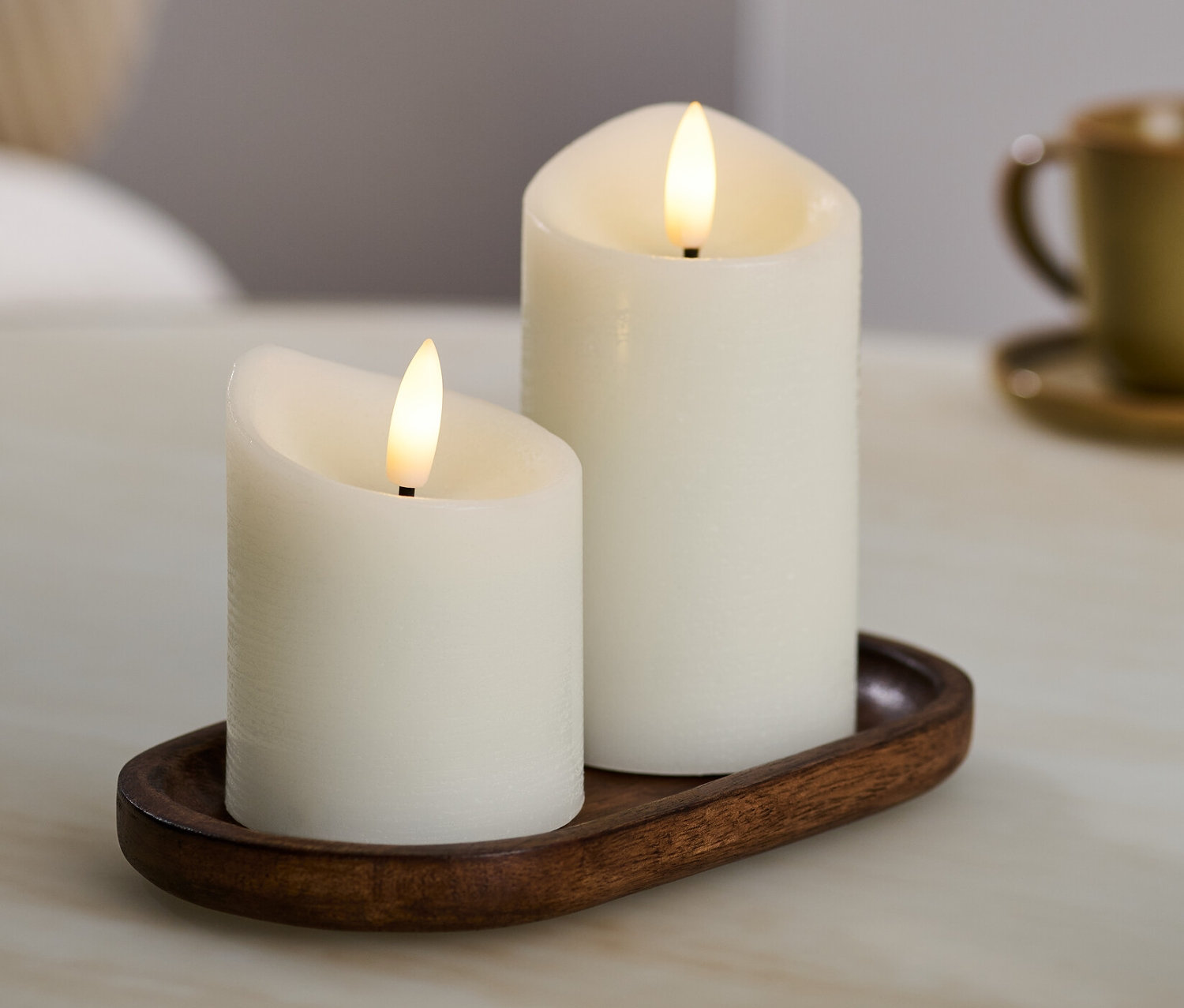 Deux bougies à LED en cire véritable crème sur un plateau marron.
