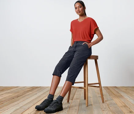 Une femme est assise sur un tabouret et porte un pantacourt technique en softshell.