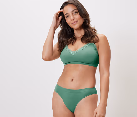 Une femme pose en sous-vêtements verts. Elle porte un soutien-gorge vert et un des 2 slips Seamless verts.