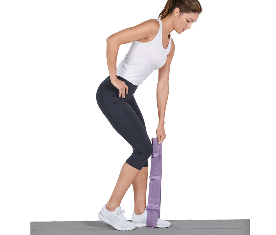 Une femme s'entraîne avec une bande de fitness ajustable, un pied dessus.