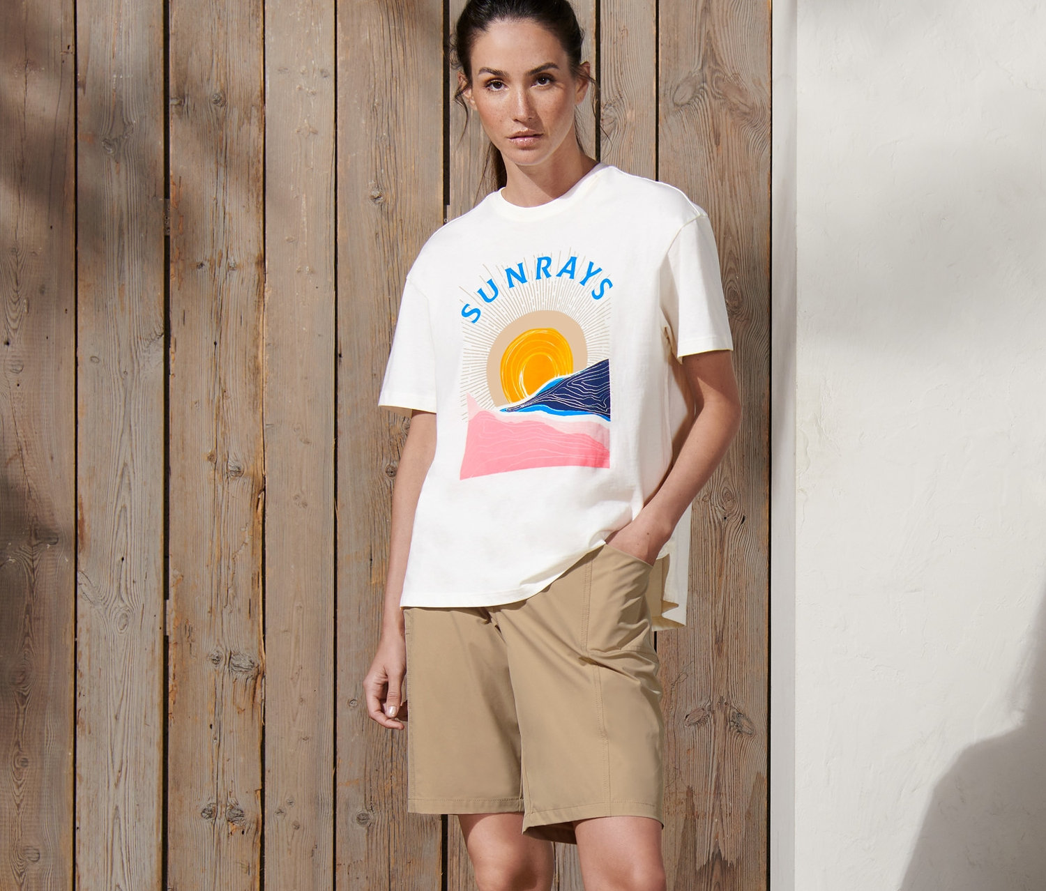 Une femme debout, la main dans la poche d'un short fonctionnel en softshell beige.