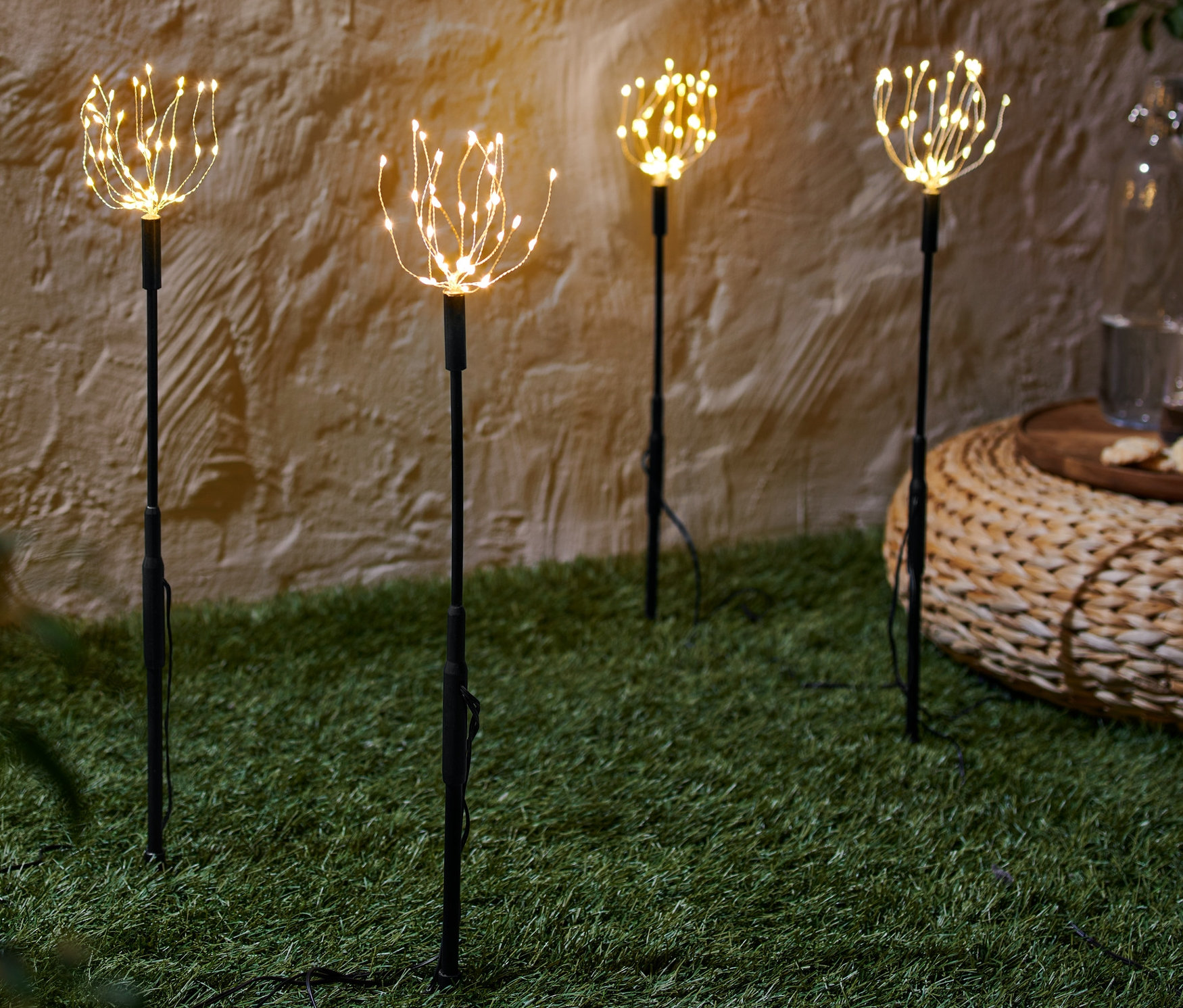 Quatre piquets de jardin à LED sont posés sur une pelouse.