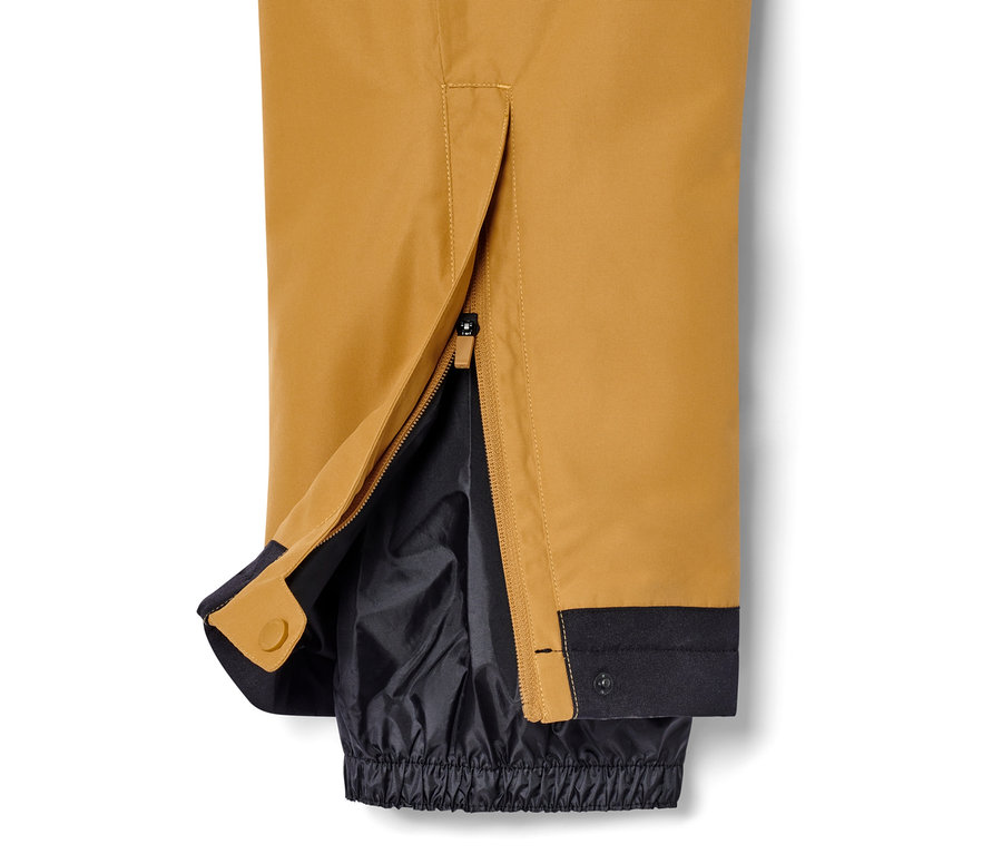 Détail d'un pantalon de ski couleur camel avec fermeture éclair ouverte à la cheville.
