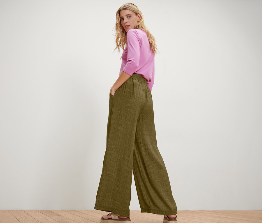 Femme posant en pantalon à taille élastique et haut rose.