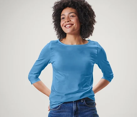 Femme posant en t-shirt bleu clair à manches 3/4 et jean bleu.