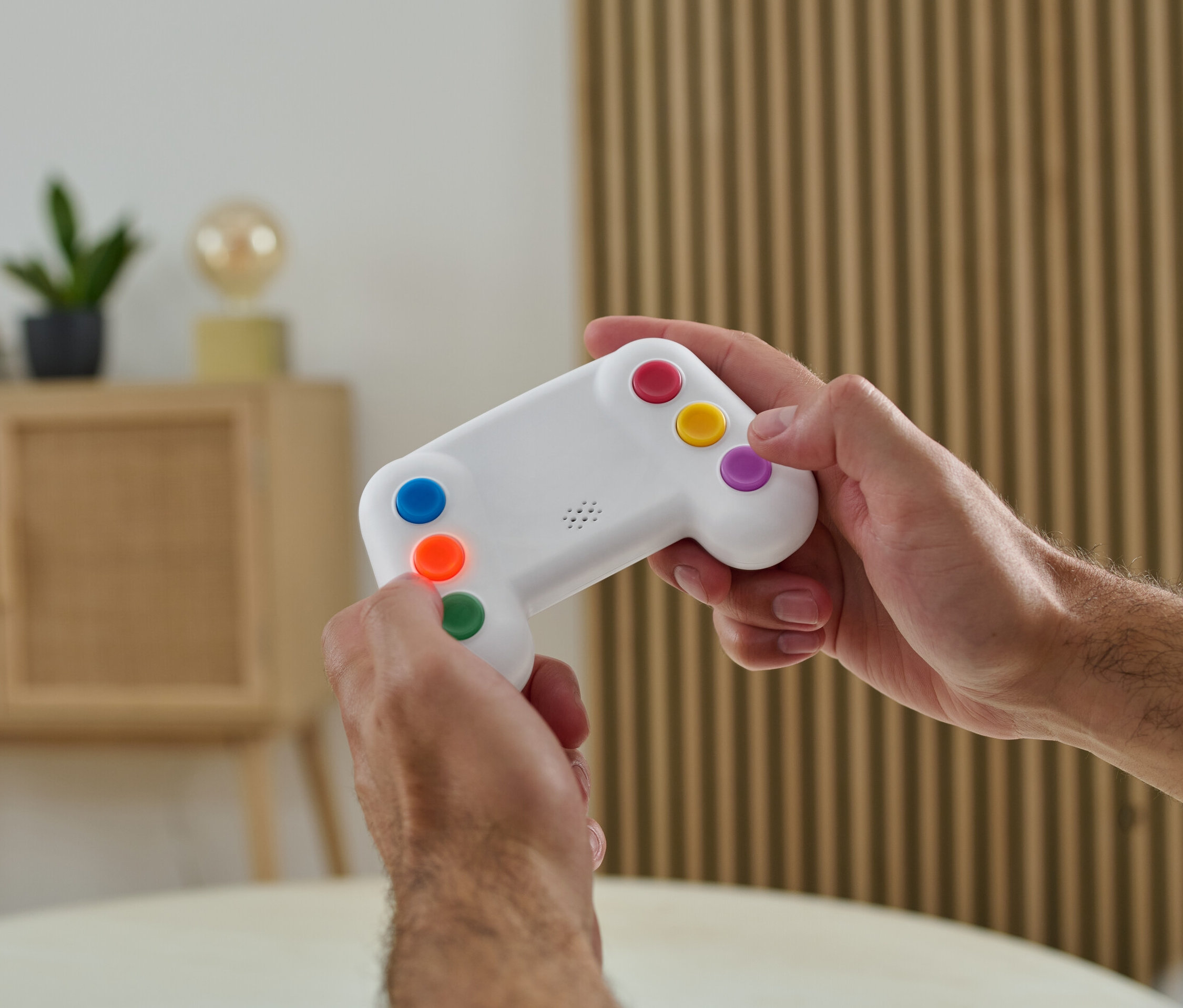 Un homme tient dans ses mains un entraîneur de mémoire électronique avec des boutons colorés.