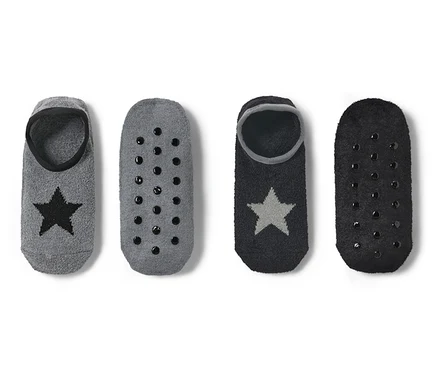 Deux paires de chaussons-chaussettes : gris avec étoile noire et semelle antidérapante, et noirs avec étoile argentée et semelle antidérapante.