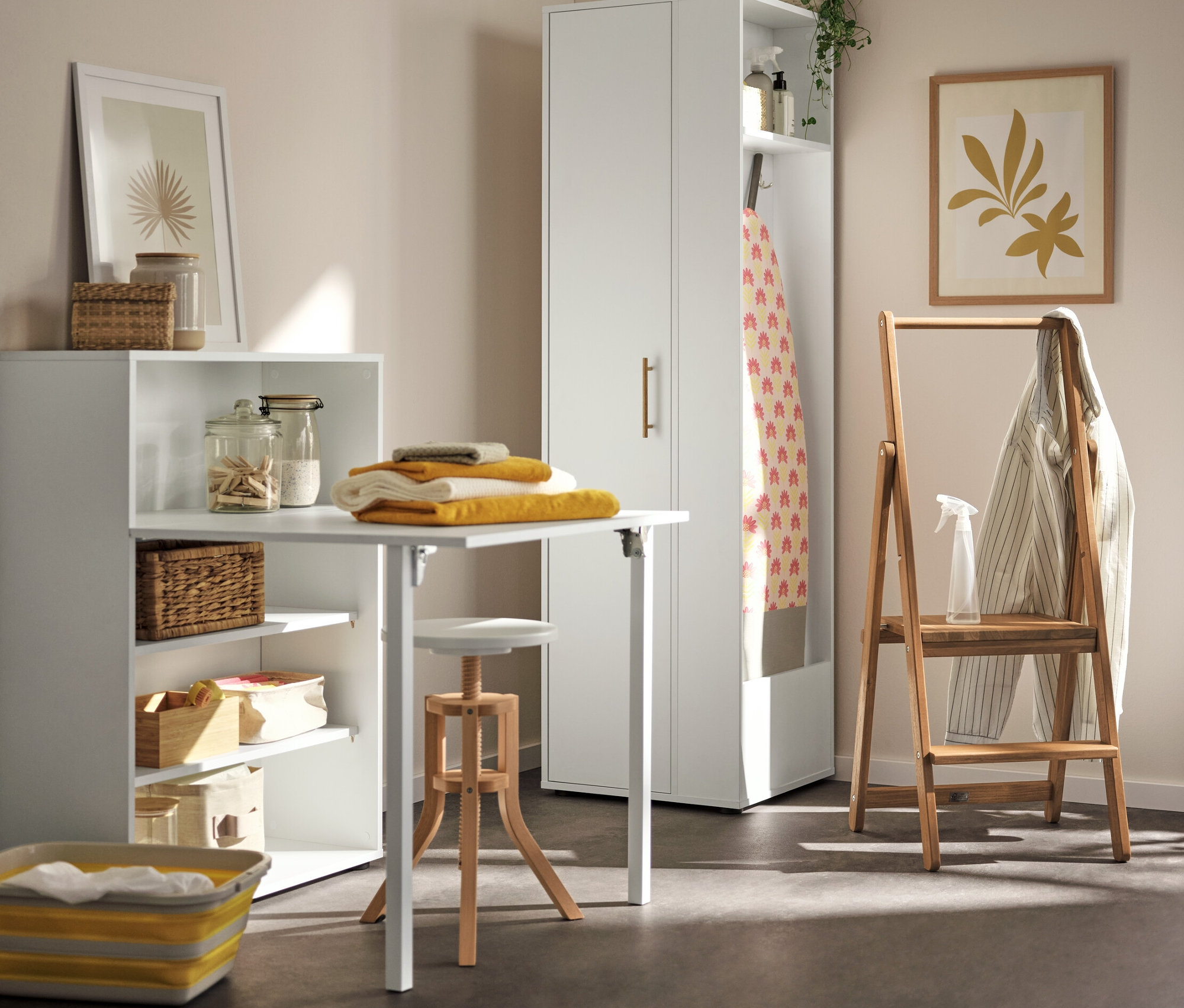 Dans la buanderie, il y a une armoire universelle avec espace de rangement latéral, une étagère avec une table pliante avec des serviettes jaunes et un escabeau en bois massif dans le coin.