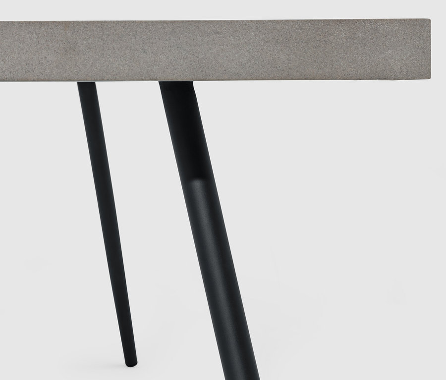 Gros plan sur une table basse avec plateau en polyciment et pieds noirs.