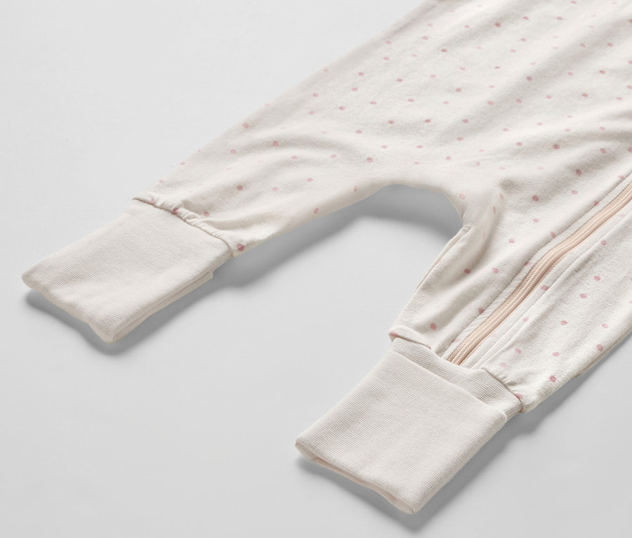 Détail d'un pyjama pour bébé avec des points roses et une fermeture éclair.