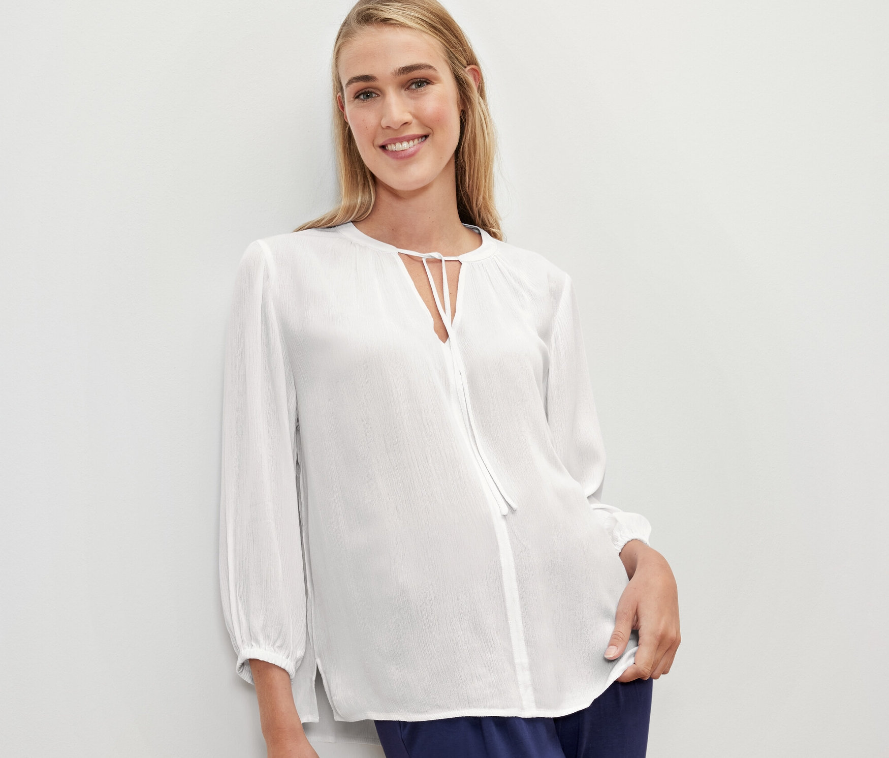 Une femme porte un chemisier-tunique blanc.