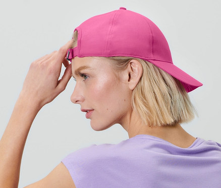Une femme blonde est assise et porte une casquette de sport.