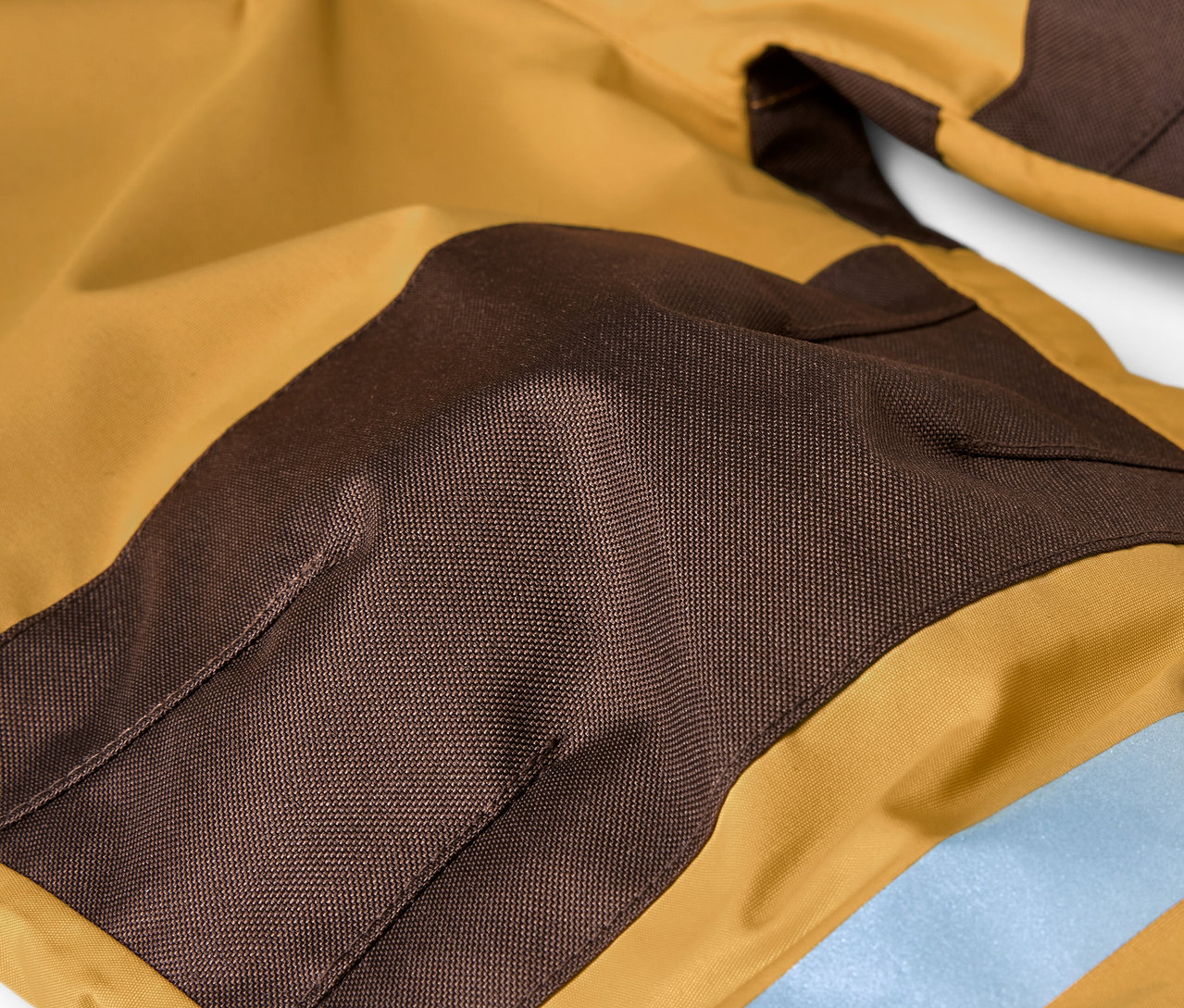 Détail d'une combinaison de pluie pour enfant en marron et ocre.