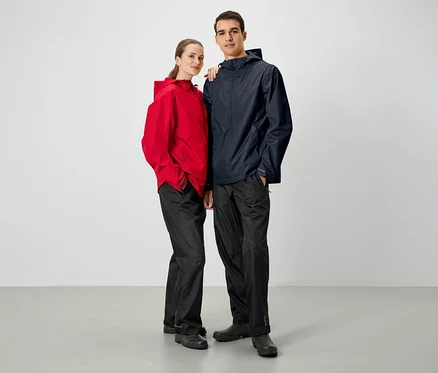 Un homme et une femme posent côte à côte. Ils portent tous deux des vestes de pluie et des pantalons noirs.