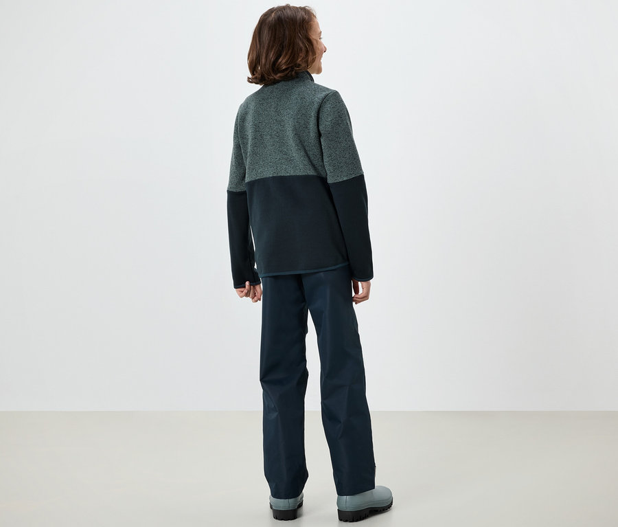 Un garçon se tient dos à la caméra et porte une veste hybride en maille polaire pour enfants.