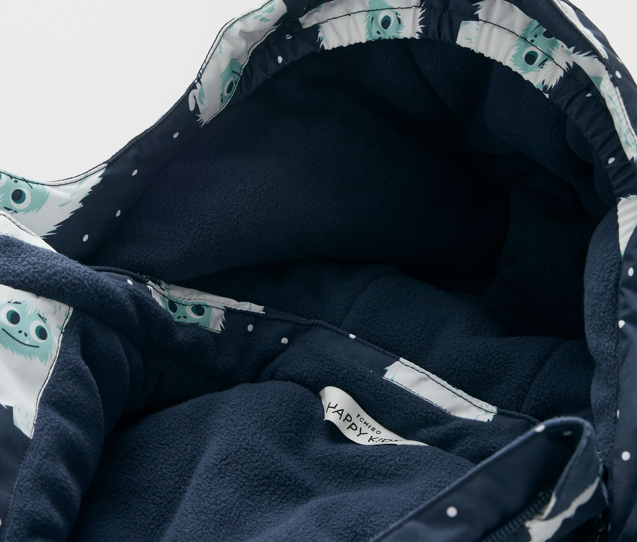 Détail d'une veste à capuche avec une doublure bleu foncé et un motif de personnages blancs.