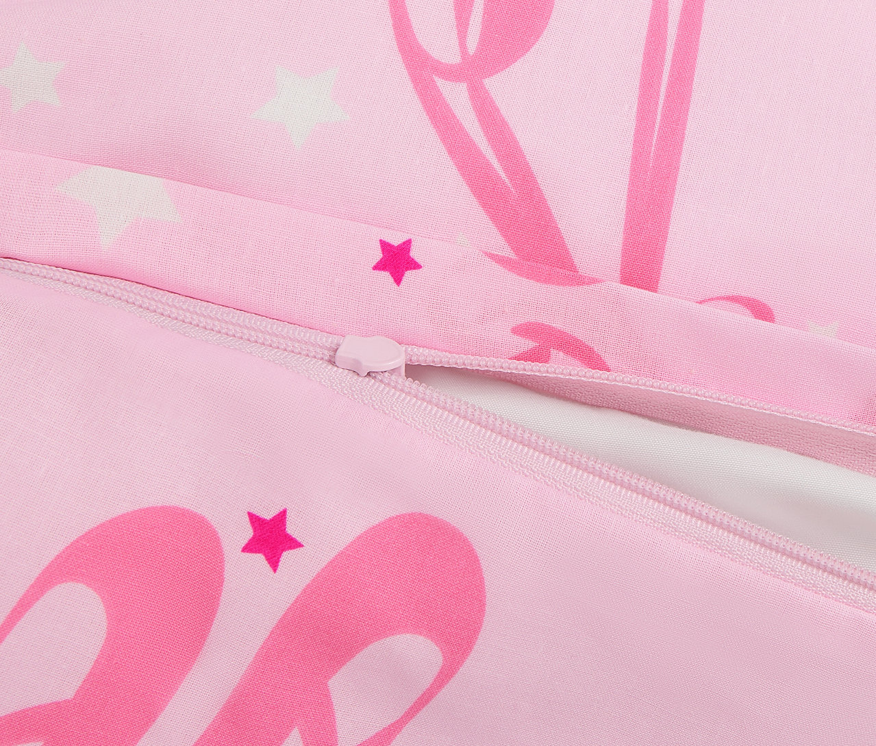 Gros plan sur une housse de couette rose avec fermeture éclair et imprimés d'étoiles et de ballerines.