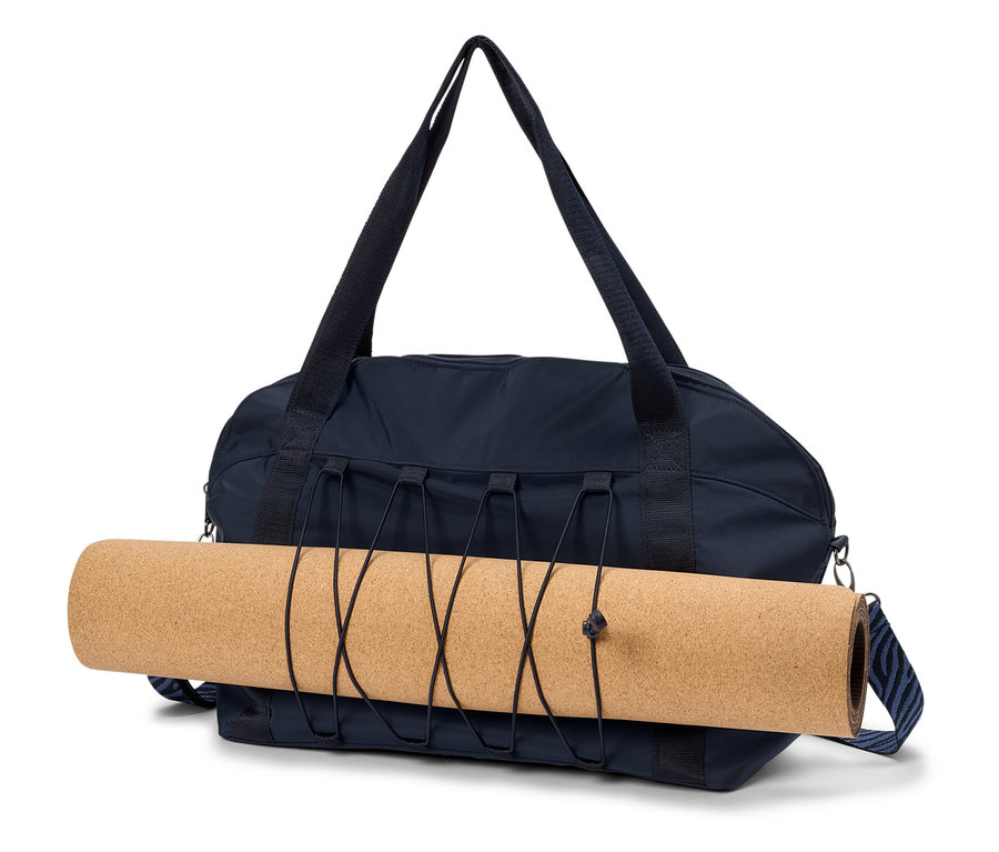 Sac de sport bleu marine avec un tapis de yoga enroulé fixé par une bande élastique.