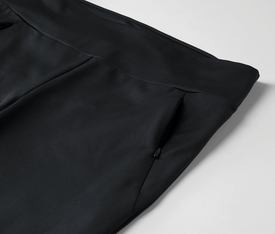 Détail d'un pantalon noir avec une poche zippée.