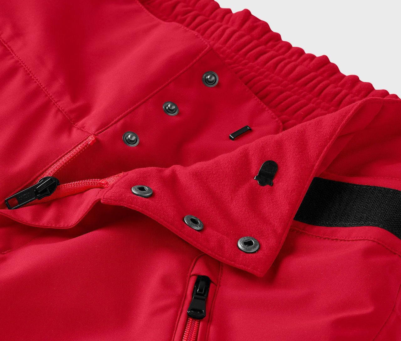 Détail d'un pantalon rouge avec fermeture éclair et boutons-pression.