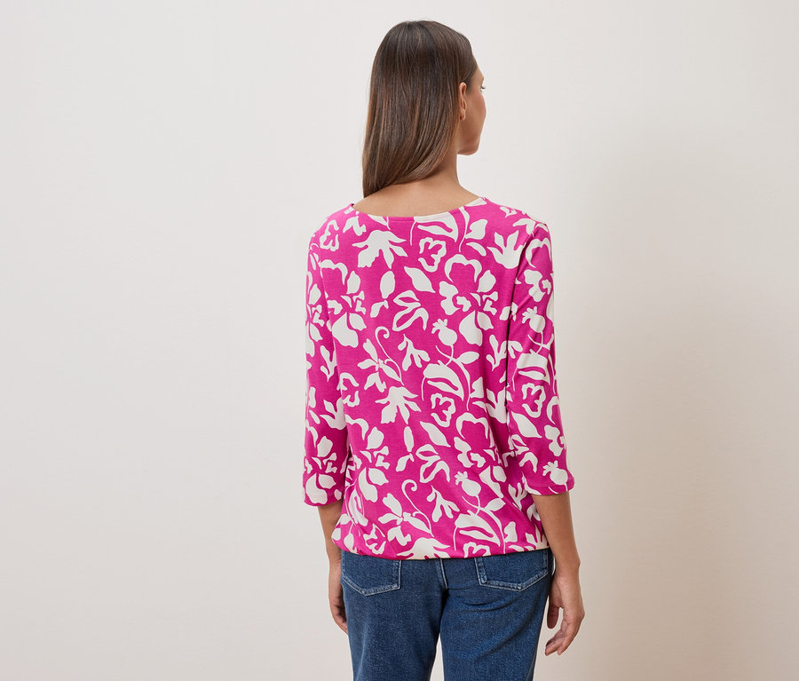 Vue arrière d'une femme portant un haut rose à motifs floraux et un jean.