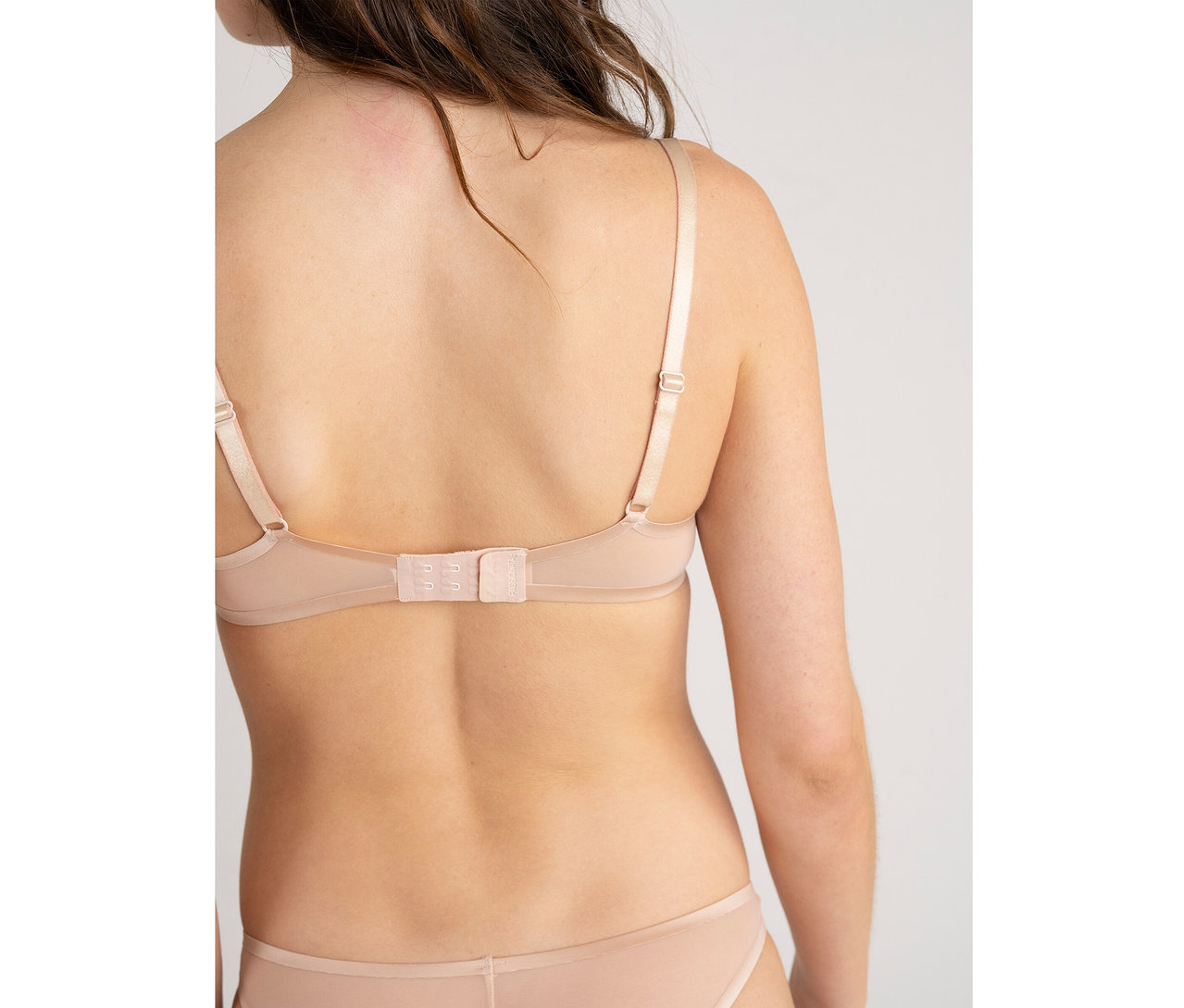 Vue de dos d'une femme portant un soutien-gorge Passionata « Bianca » couleur dune et une culotte assortie.