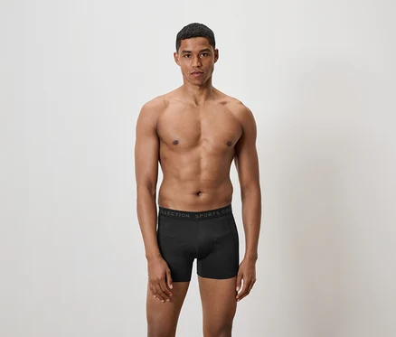 Homme torse nu posant en boxer noir.