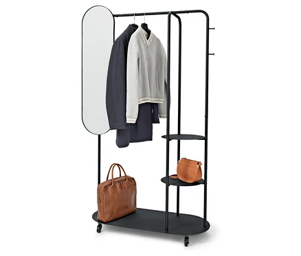 Porte-vêtements noir avec miroir ovale, manteau, pull, pantalon et deux sacs marron.