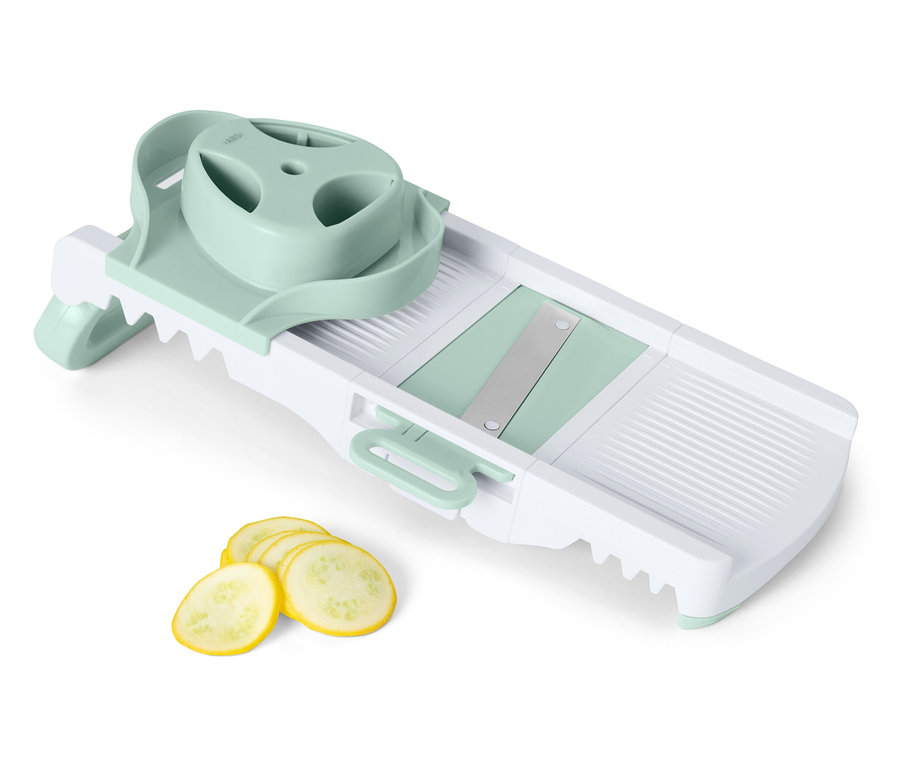 Mandoline à légumes avec des tranches de courgette jaune.