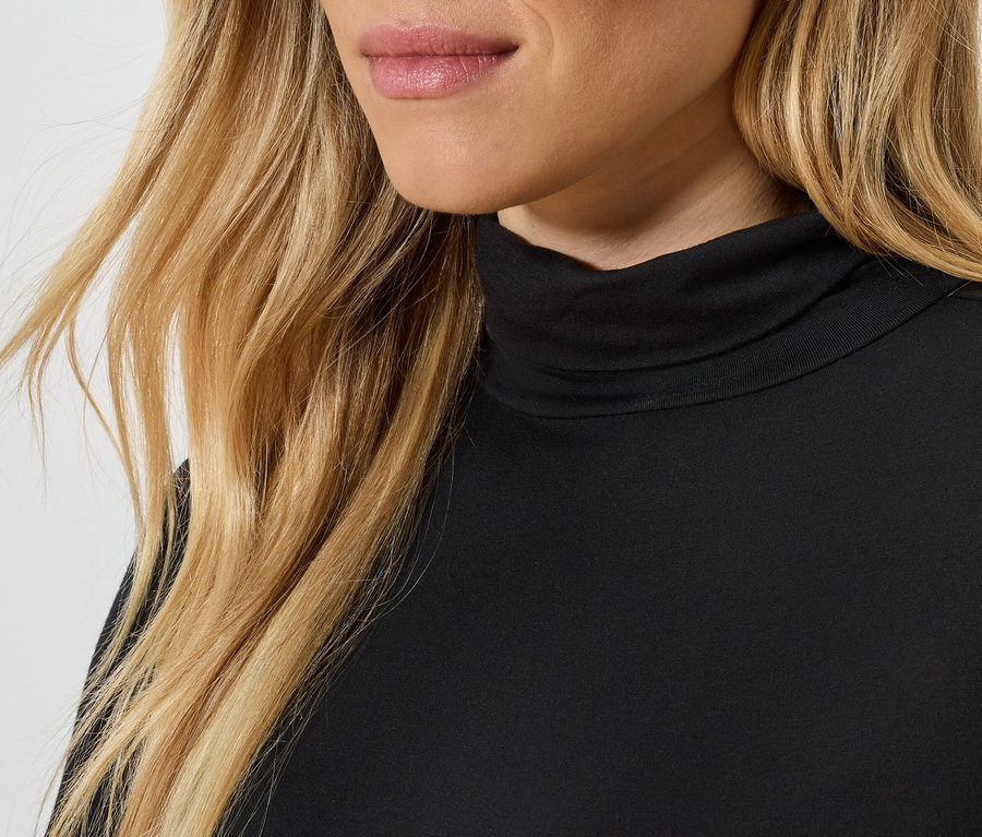 Gros plan d'une femme blonde portant un col roulé noir.