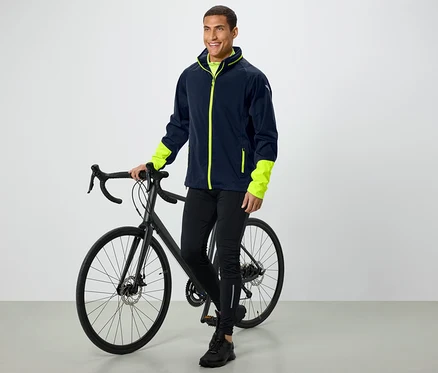 Un homme se tient à côté d'un vélo et porte une veste avec des manches néon.