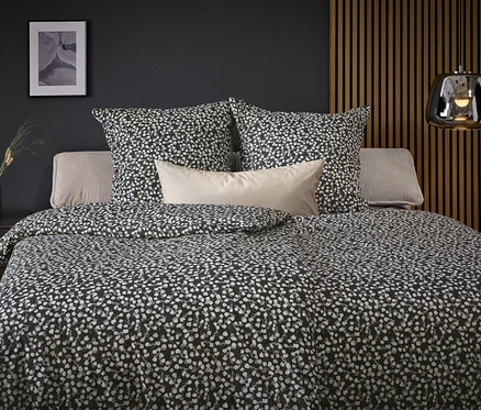 Linge de lit à motifs noirs et blancs sur un lit avec des oreillers.