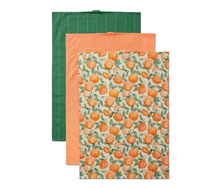 Un ensemble de 3 linges de cuisine : un vert à rayures, un orange et un blanc avec un imprimé d’oranges.