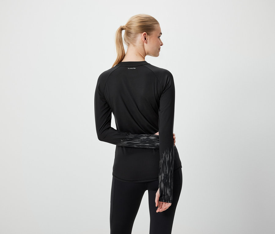 Vue de dos, une femme blonde portant une queue de cheval et des vêtements de sport noirs.