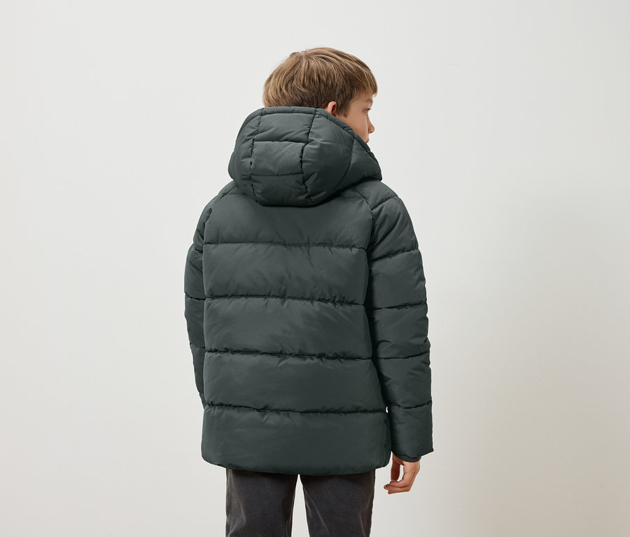 Garçon portant un manteau rembourré vert foncé avec une capuche, tourné vers l'arrière.