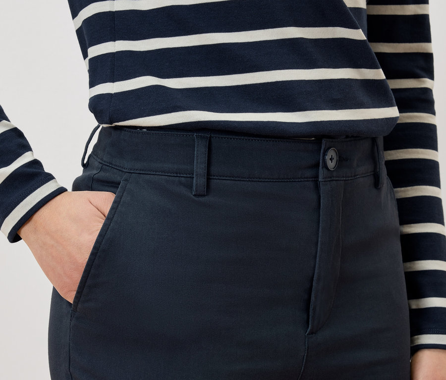 Gros plan d'une personne avec une main dans la poche de son pantalon et un T-shirt rayé.