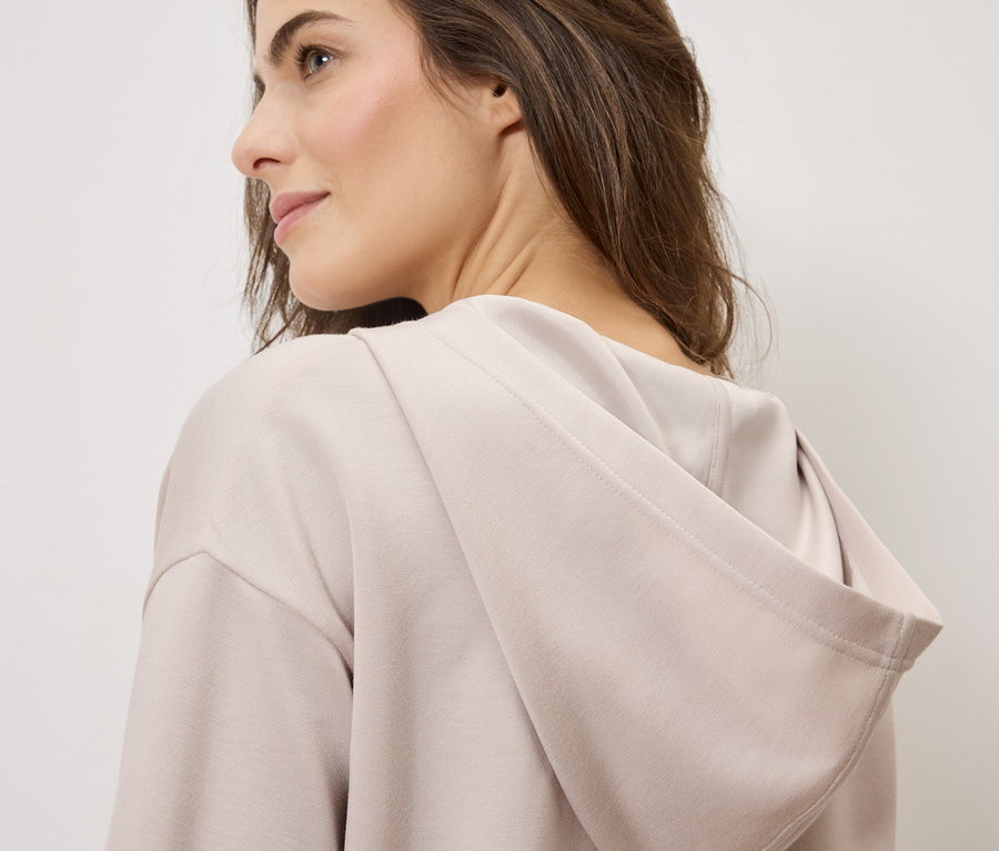 Femme portant un sweat à capuche marron clair.