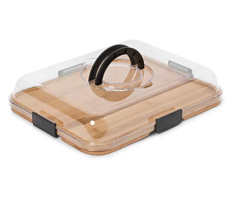 Une planche à découper rectangulaire en bambou avec un couvercle transparent et une poignée noire repose sur une surface blanche.