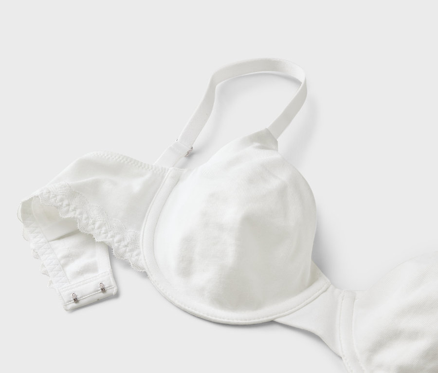 Gros plan d'un soutien-gorge blanc avec bretelles réglables et fermeture à agrafes sur fond clair.