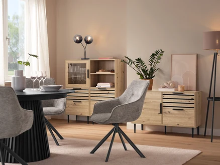 Salle à manger avec table à manger, chaises grises, vitrine »BAAKEN« avec porte en verre, étagère »BAAKEN« avec tiroirs et buffet avec tiroirs.