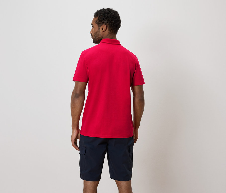 Homme vu de dos, portant un polo rouge et un short bleu.